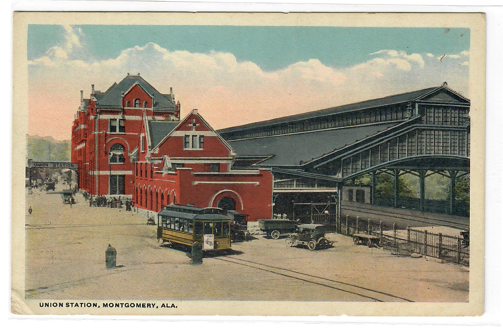 Montgomery Union Station, Alabama — red brick depot with streetcar, early cars, and large glass train shed in background.