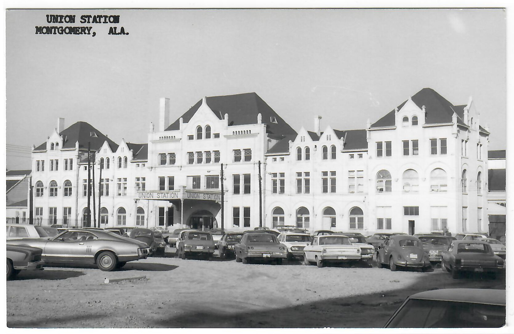 Black-and-white photo postcard of Montgomery Union Station, Alabama, with arched windows and 1960s–70s cars in front.